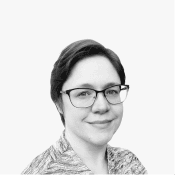 A black and white portrait of a woman with short dark hair and glasses, smiling gently, embodying the professional and.