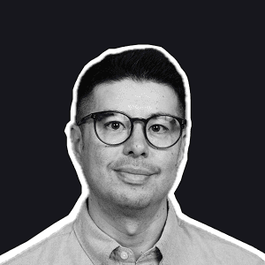 A smiling man with stylish glasses and a short haircut, wearing a collared shirt, representing a Birdie support lab expert.