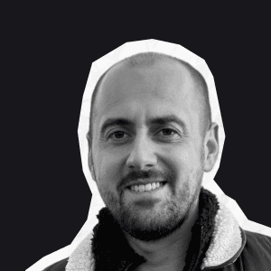 A smiling man with a beard and short hair, wearing a jacket with a fluffy collar, embodies the friendly support at Birdie.
